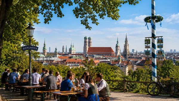 Münchner Biergarten mit Trachtbesuchern und Blick auf die Skyline